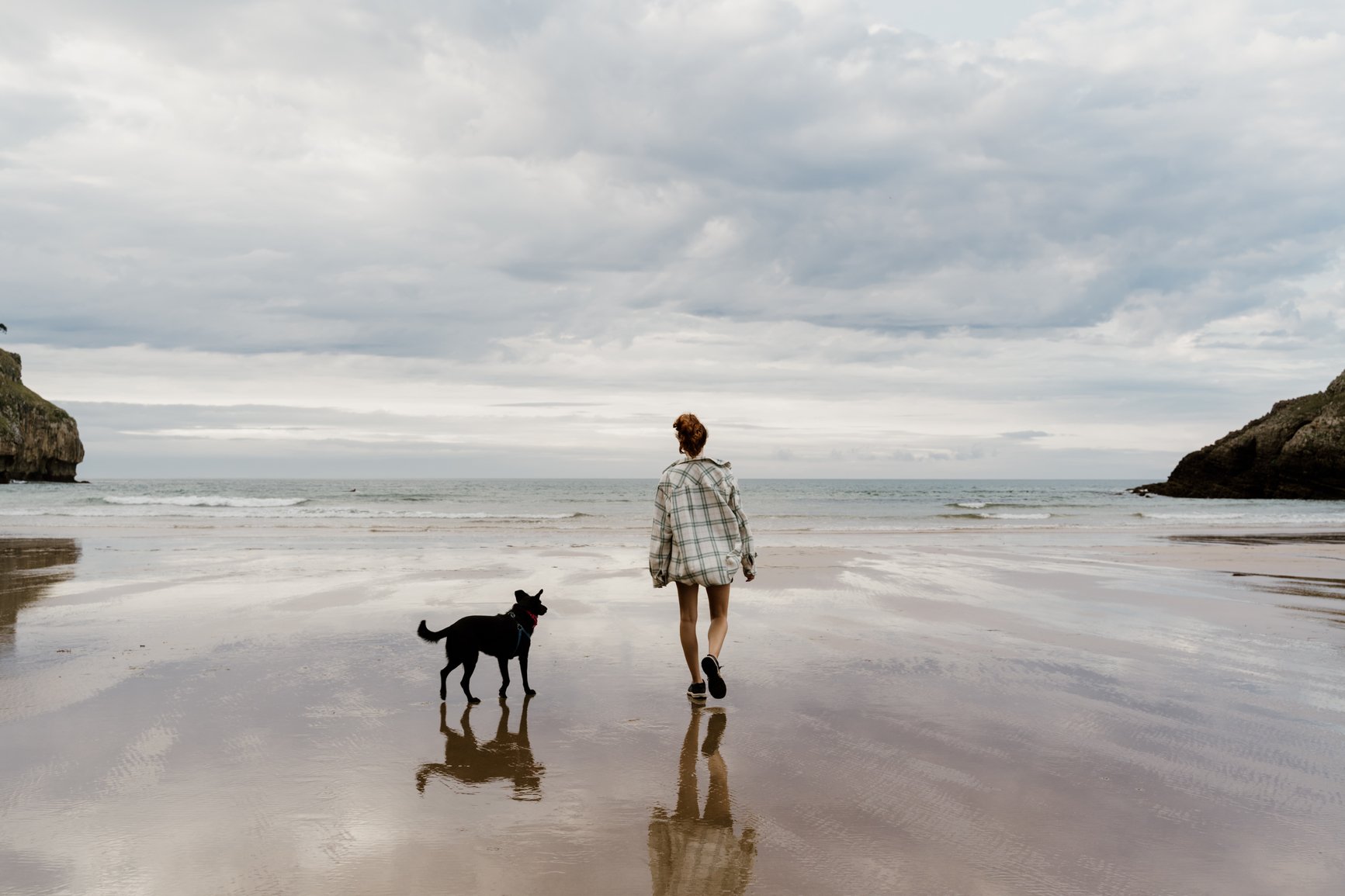 woman walking dog beach